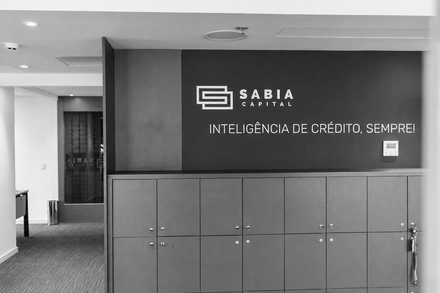 Recepção do escritório da Sabia Capital em preto e branco com o slogan Inteligência de crédito, sempre!